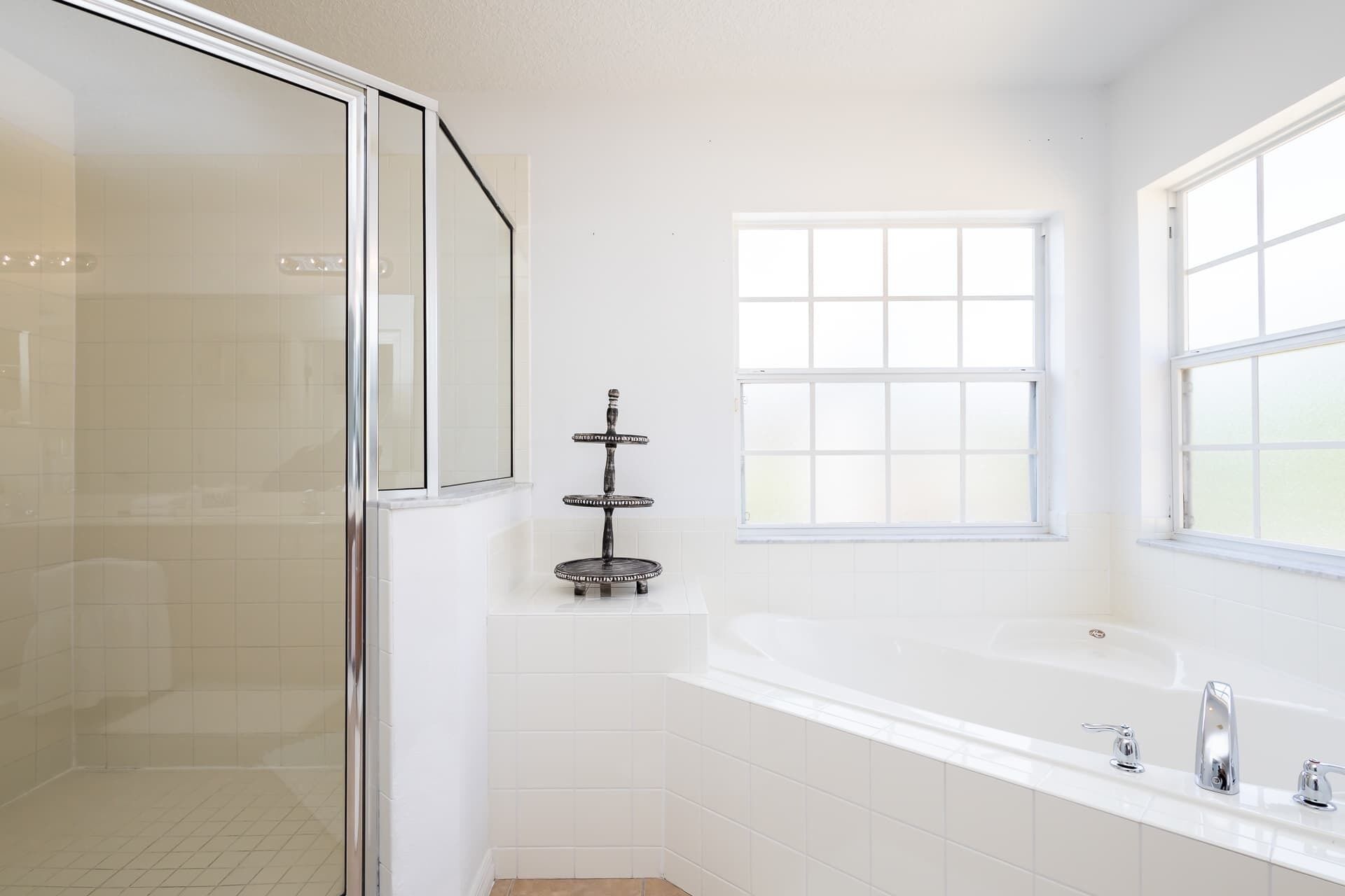 A modern bathroom with a glass shower enclosure, a freestanding bathtub, and a window providing natural light.