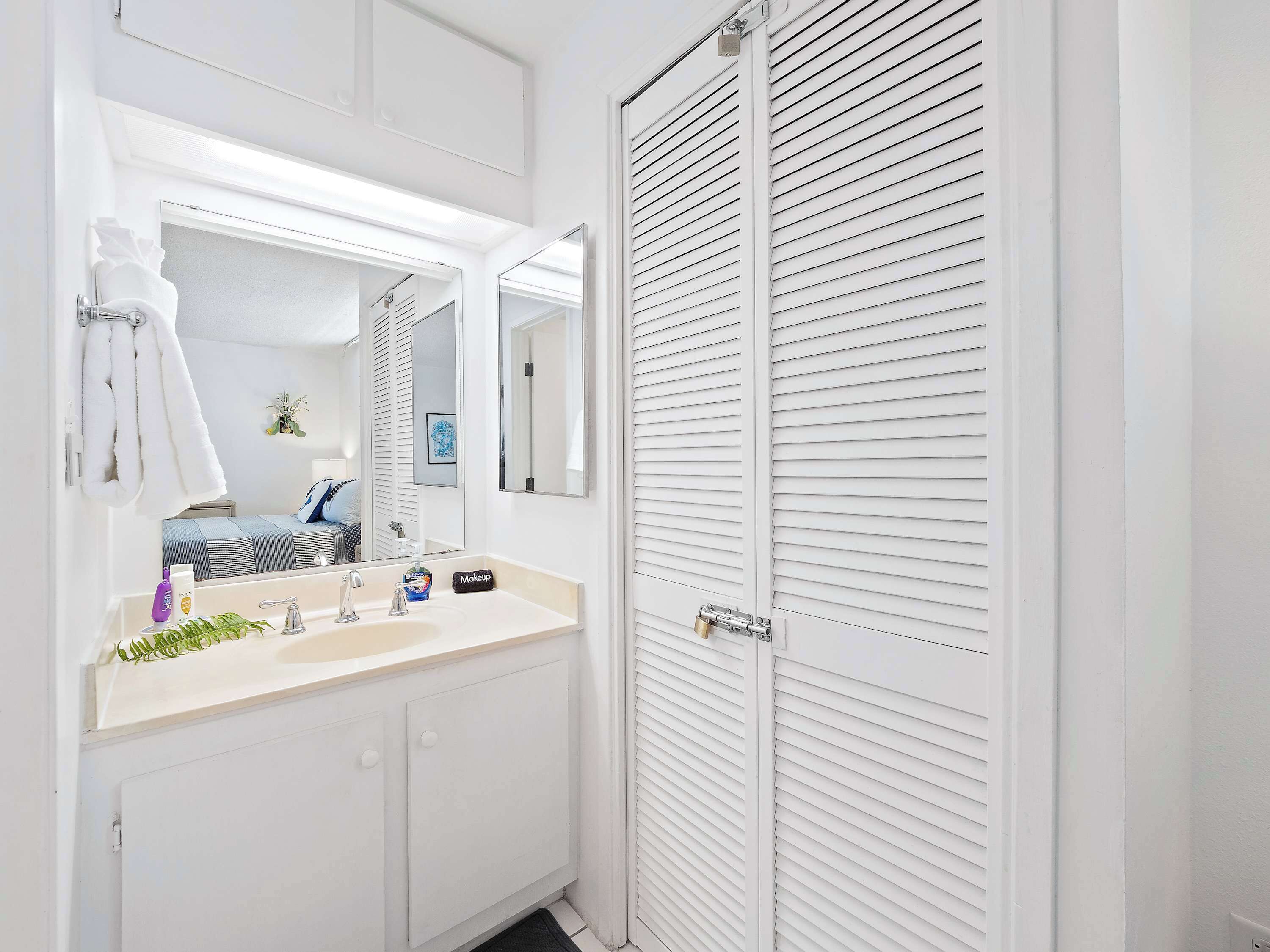 Een badkamer met een witte wastafel, een spiegel en een handdoekrek.