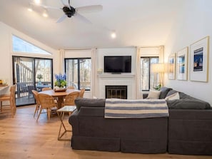 A living room with a sofa, a fireplace, a television, and a dining area with chairs and a table.