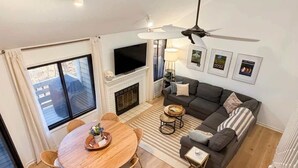 Una sala de estar con chimenea, un sofá, un televisor y un comedor con sillas y una mesa.