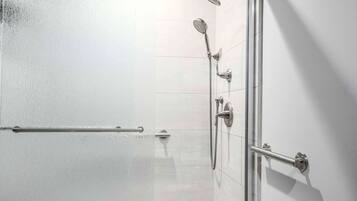A shower area with a handheld showerhead, a wall-mounted showerhead, and a handheld shower attachment.