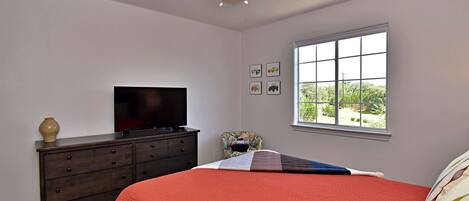 A bedroom with a bed, dresser, television, and window.