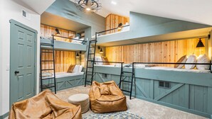 A multi-level bunk bed room with wooden paneling, a ladder, and two bean bags. - Penthouse 7 on Taneycomo - Chic Waterfront Condo! (Branson)