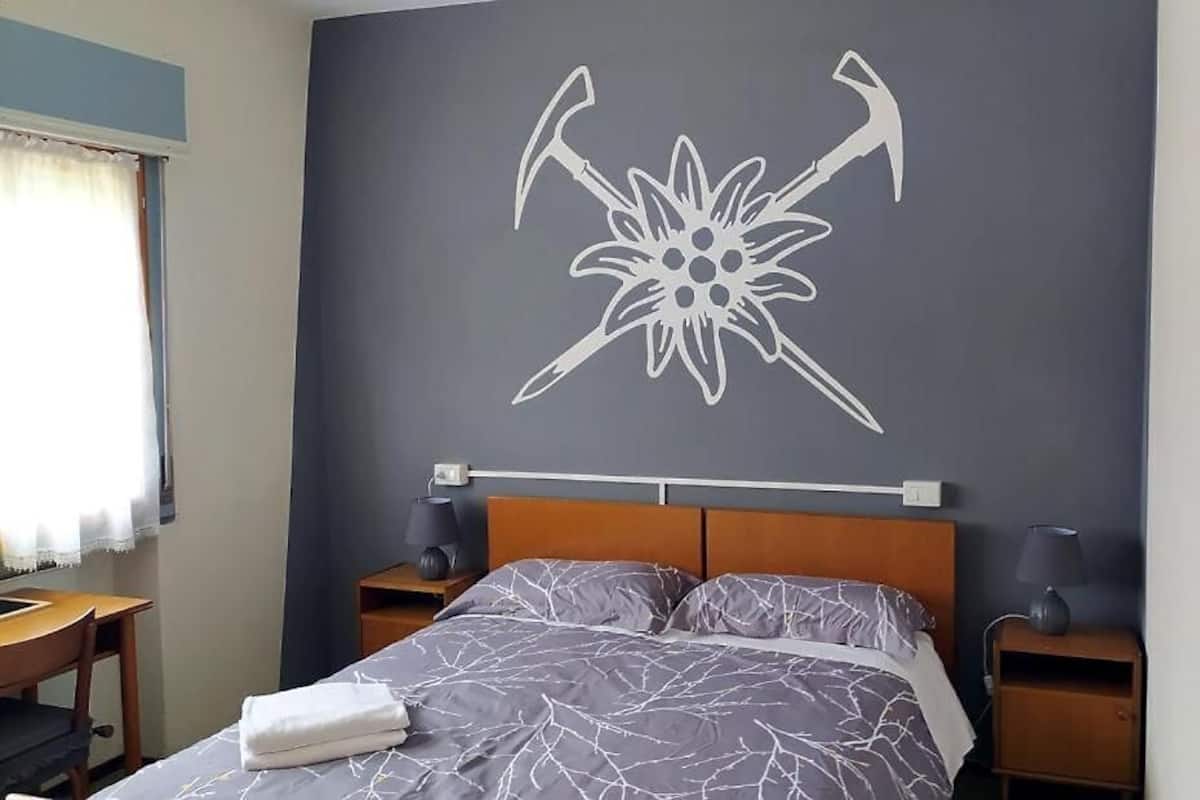 A bedroom with a bed, two bedside tables, a headboard, and a wall decoration.