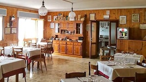 Un ristorante con pareti in legno, una cucina centrale e tavoli apparecchiati per consumare i pasti.