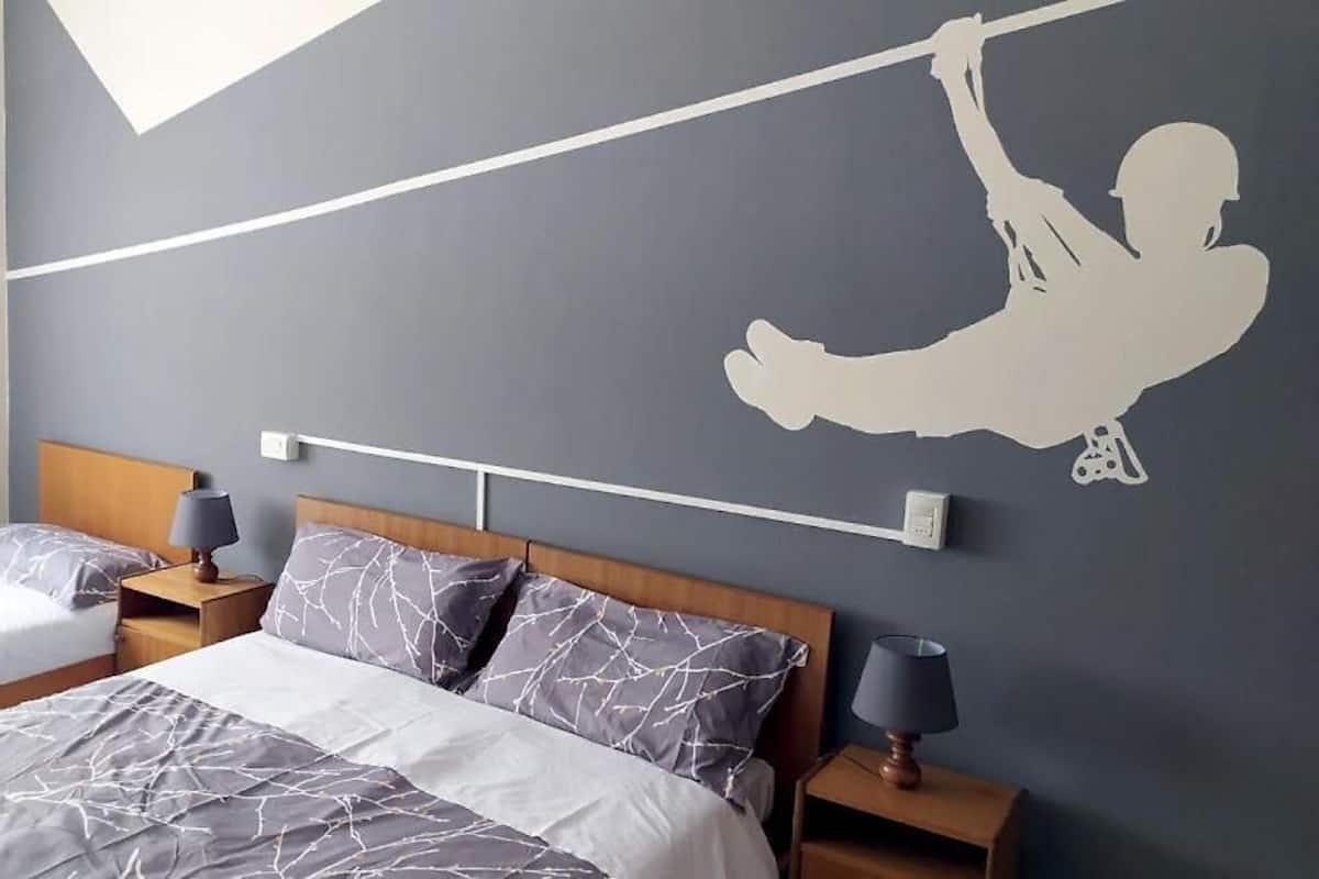 A hotel room with two beds, a wooden headboard, and a wall mural of a person swinging.