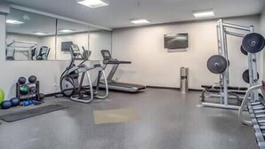 Une salle de sport équipée de tapis de course, de vélos elliptiques et de matériel de musculation.