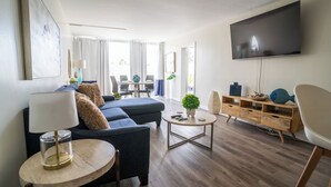 Uma sala de estar moderna com sofá, mesa de centro, televisão e armário de madeira.
