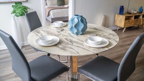 Uma sala de jantar com uma mesa de mármore, cadeiras pretas e um vaso azul.
