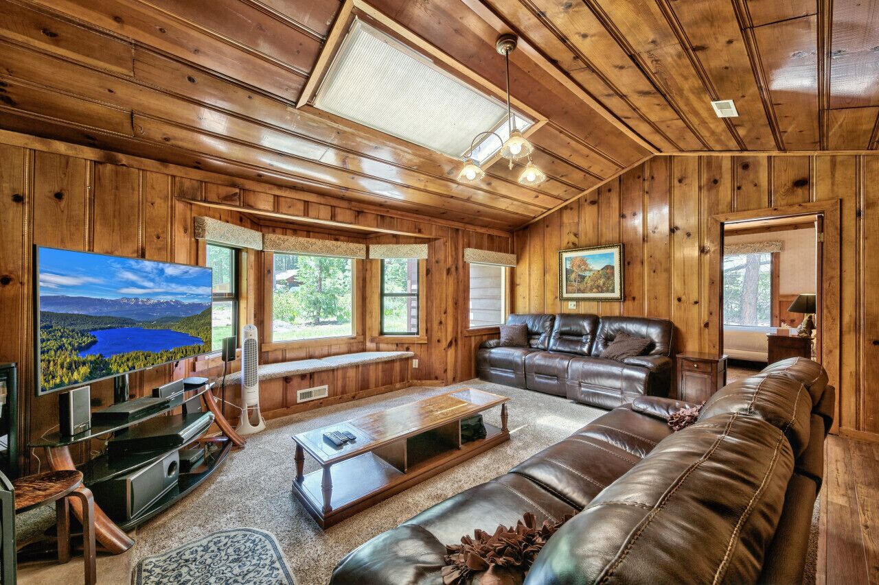 Ein Holzinterieur mit einem großen Fernseher, einer Ledersofa und einem Kamin.