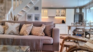 Un salon moderne comprenant un canapé, un coin repas, une cuisine et un escalier.