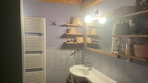A bathroom with a white sink, mirror, and shelves with baskets. - 2 Bedroom Apartment in Gionghi-cappella (Gionghi-cappella)