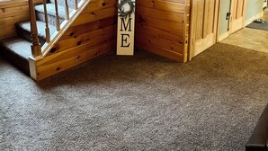 Un interior de madera con una escalera, un cartel de bienvenida y una puerta.