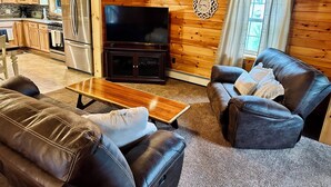 Una sala de estar con interior de madera, un televisor de pantalla plana, sofás de cuero y una mesa de centro.