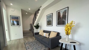 Un salon moderne avec un canapé gris, une petite table ronde et un escalier menant à un autre niveau.
