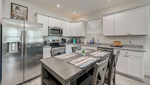 A modern kitchen with white cabinets, stainless steel appliances, and a granite countertop.