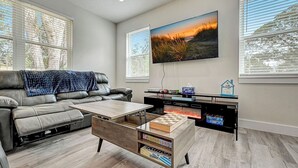 A modern living room with a leather sofa, a coffee table, and a flat-screen TV mounted on the wall.