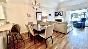 Una sala de estar moderna con comedor, chimenea y televisor.