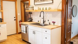 A kitchen with white cabinets, a black sink, and a wooden countertop. - Cute 2-bed home, 3 blocks from downtown Bozeman, with a large yard! (Bozeman)