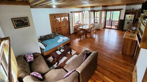 Une pièce spacieuse avec un plafond en bois, un canapé, une table à manger et un coin cuisine.