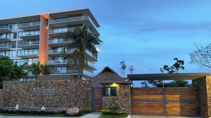 A modern residential building named Altamor with a stone facade, a wooden gate, and a well-maintained lawn. - En el mar la Vida es más Sabrosa y en Altamar Residencial más (Acapulco)