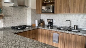 A modern kitchen with granite countertops, a stainless steel range, and wooden cabinets. - En el mar la Vida es más Sabrosa y en Altamar Residencial más (Acapulco)