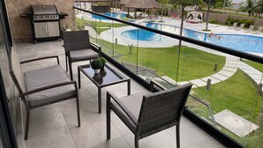A balcony with a grill, seating, and a view of a swimming pool. - En el mar la Vida es más Sabrosa y en Altamar Residencial más (Acapulco)