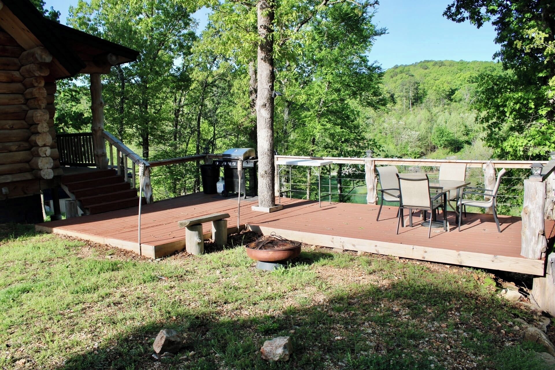 A wooden deck with outdoor furniture, a grill, and a fire pit.