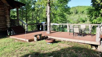 A wooden deck with outdoor furniture, a grill, and a fire pit.