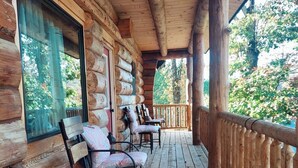 A wooden cabin with a porch featuring four chairs and a table. - Spring Pond Cabin at White Buffalo Lodge;
Family-sized with lake access (Grove)