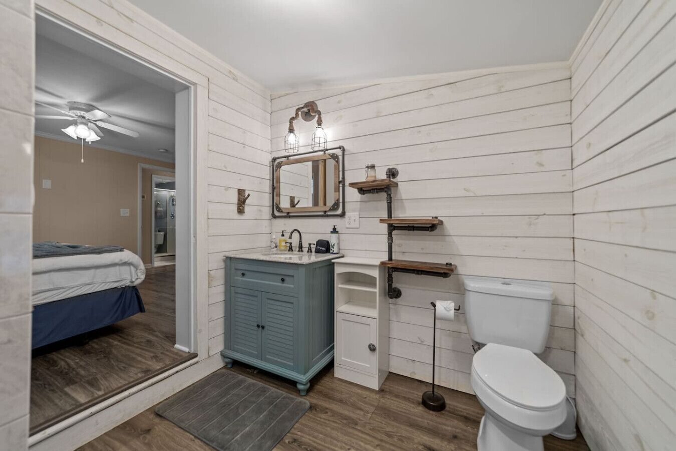 Ein kleines Badezimmer mit Toilette in Weiß, einem blauen Waschtisch, einem Spiegel und einer Duschkabine.