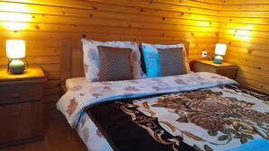Een kamer met houten lambrisering, een bed, twee nachtkastjes en twee wandlampen.