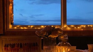 Ein Tisch gedeckt mit Kerze, Blumen in einer Vase und einer Speisekarte.