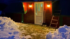 Eine kleine Holzhütte mit Tür und Fenstern, umgeben von Schnee.
