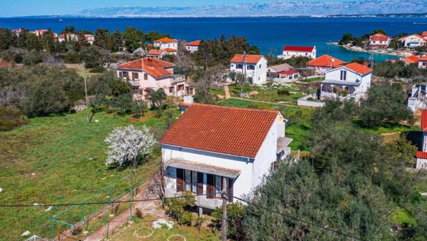 A coastal village with houses featuring red-tiled roofs, surrounded by greenery and a clear view of the sea. - Two Bedroom Apartment with Terrace (Ugljan)