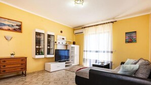 A living room with a sofa, TV, and storage units against yellow walls. - Two Bedroom Apartment with Terrace (Ugljan)
