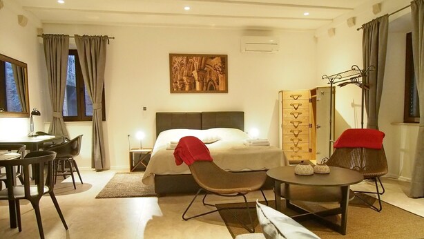 A hotel room with a bed, a desk, a chair, a sofa, a dining table, and a wardrobe. - Luxury Style Apartments - Studio Apartment (Elegant) (Dubrovnik)