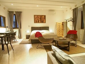 A hotel room with a bed, a desk, a chair, a sofa, a dining table, and a wardrobe. - Luxury Style Apartments - Studio Apartment (Elegant) (Dubrovnik)