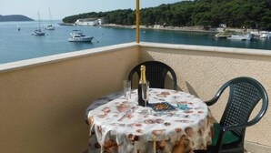 Un balcón con una mesa preparada para dos personas, con mantel decorado con motivos de concha, una botella de champán y una copa.