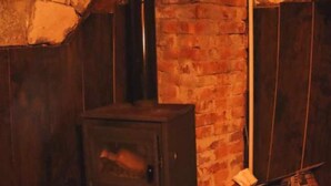 A rustic room with a brick wall, a wooden stove, and a wooden door.
