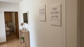 Un pasillo con una consola de madera, un espejo y dos letreros enmarcados en la pared.