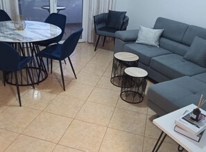 Enjoy dining and relaxation in this inviting living space with a central table, comfortable sofa, and ample surface space.