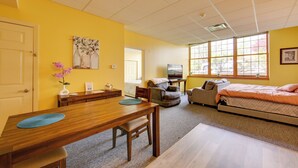 A room with a wooden dining table, a sofa, a bed, and large windows. - New Kensington Apt Near Parks: Pets Welcome! (New Kensington)