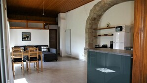 Una cocina con arco de piedra, sillas de madera, un sofá y una mesa de comedor.