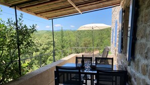 Un balcón con mesa y sillas, con vistas a un paisaje verde exuberante.