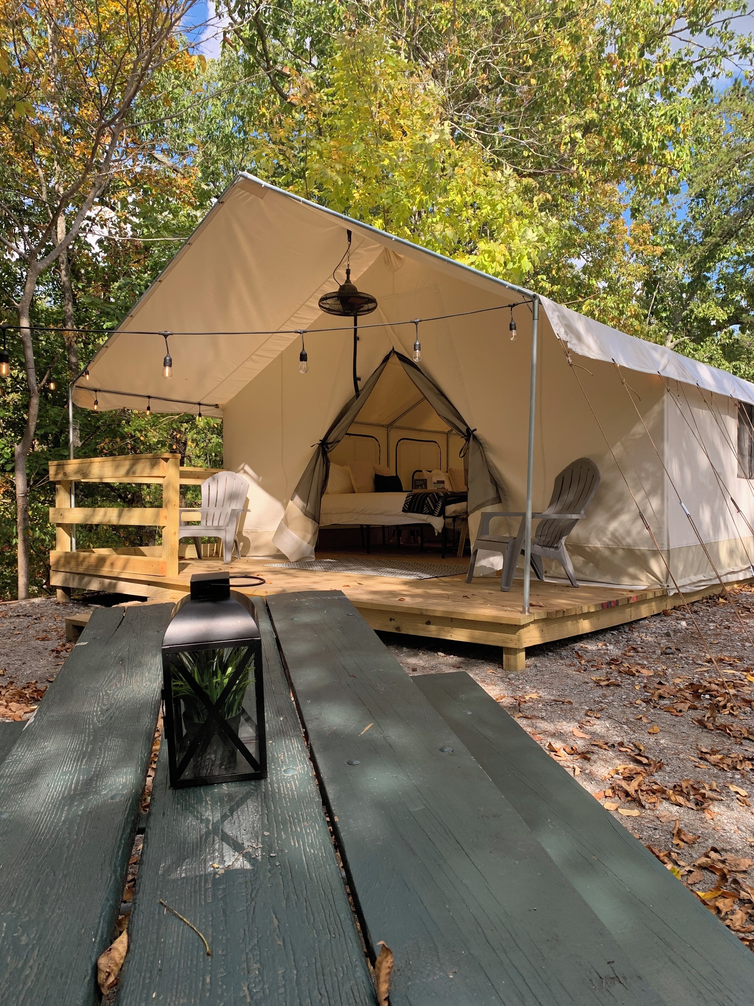 Eine Zelthütte mit Bett, Sitzecke und einer Laterne auf einer Holzplattform.