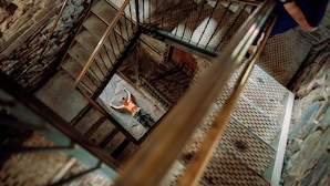 A person standing on a metal staircase with a mesh railing, surrounded by stone walls and a wooden floor. - Timberline Glamping Cheaha (Delta)