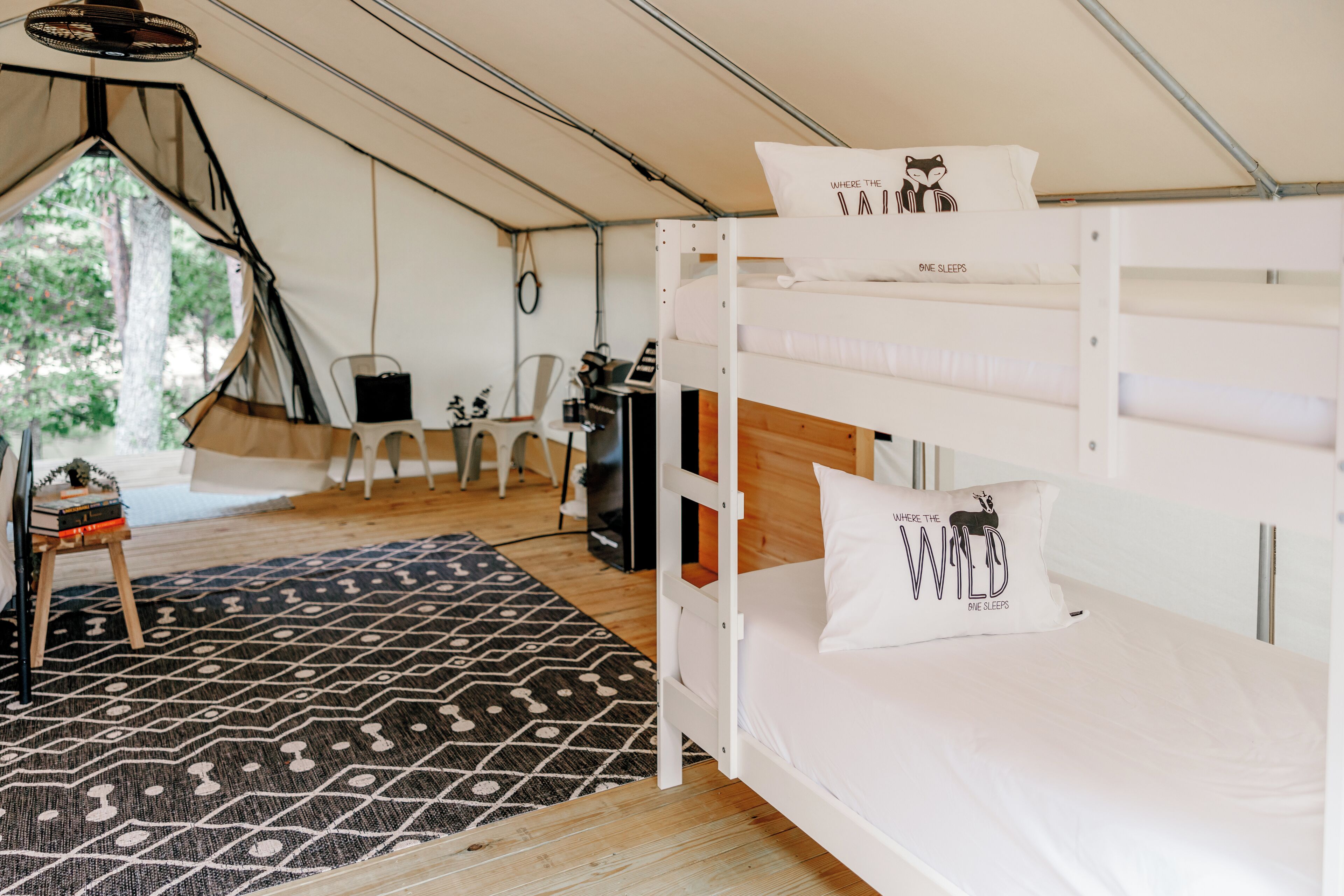 Eine Unterkunft mit Zelt, Etagenbett, einem gemusterten Teppich und einem Schreibtisch mit Stuhl.