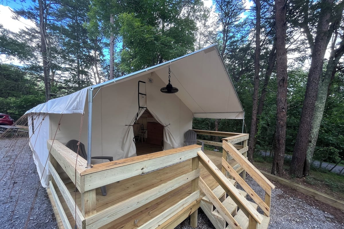 A wooden structure with a tent-like roof, a wooden staircase, and a small table.