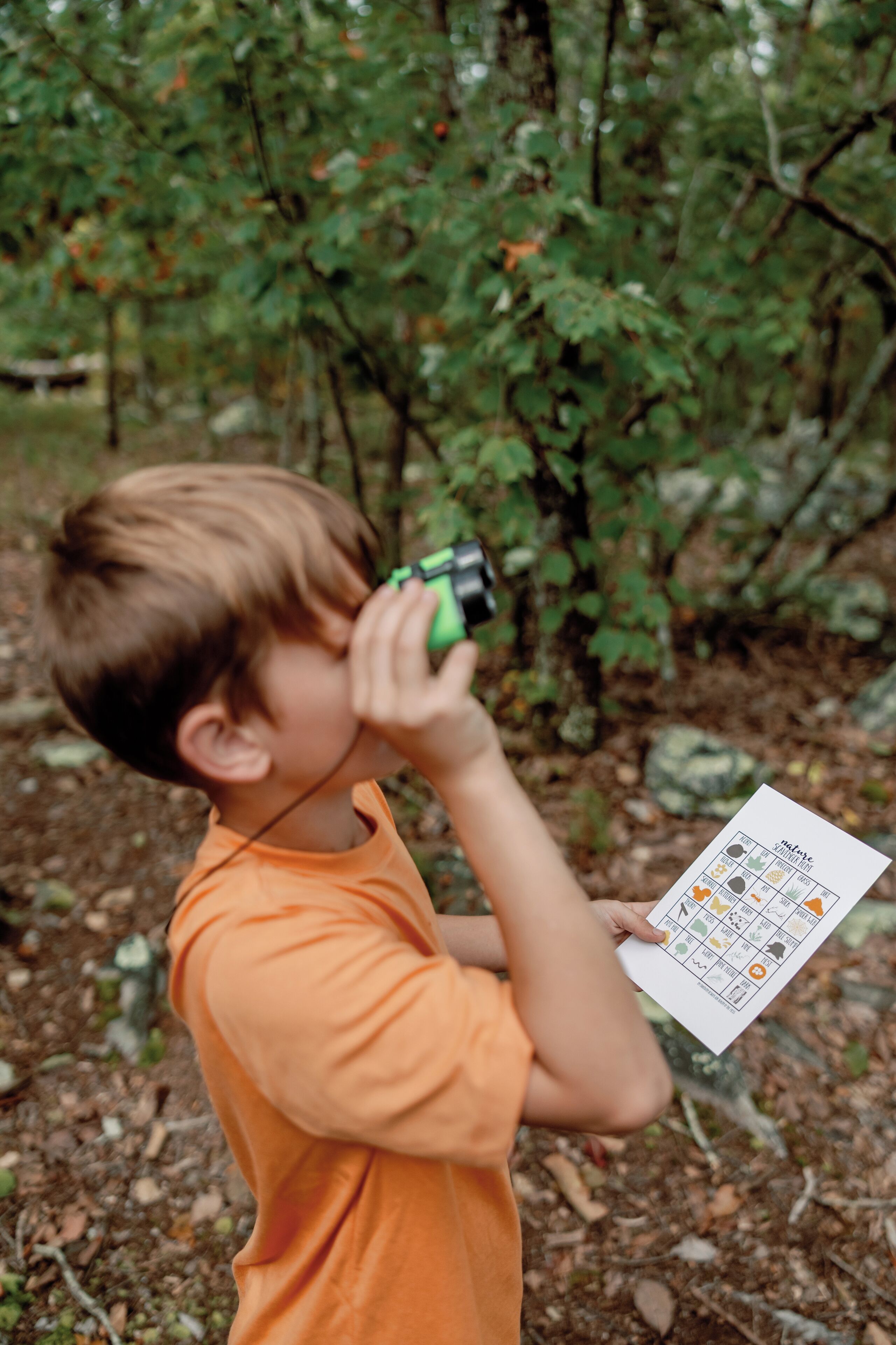 A child holding a green object and a card with icons.